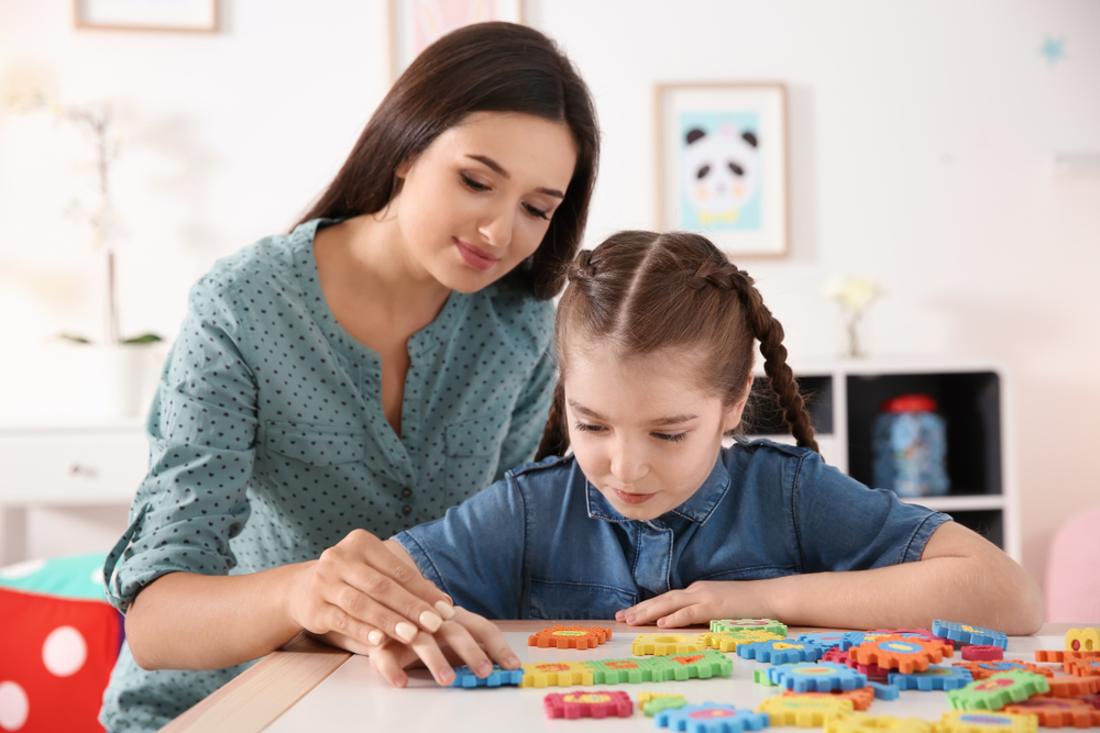 Young-woman-and-little-girl-with-autistic-disorder-playing-at-home (1)